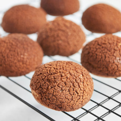 Freshly baked cream puffs with golden crisp tops arranged neatly on a cooling rack.