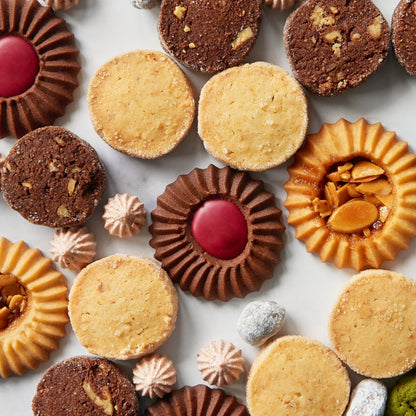 Alt Text: Assorted handmade cookies from C by C New York, including buttery sablés, chocolate cookies with red centers, and almond florentines, beautifully arranged on a white surface.